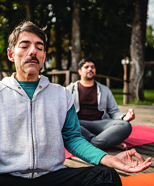 Mature man meditating with friends on the pier outdoors