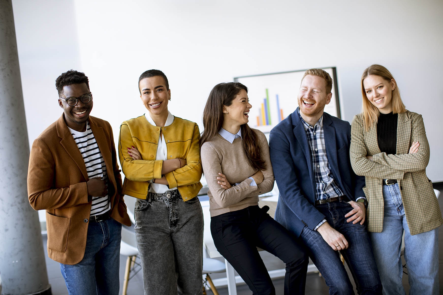 Group of young positive business people standing together in the office