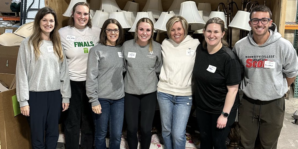 Seven coworkers posing at warehouse volunteer event