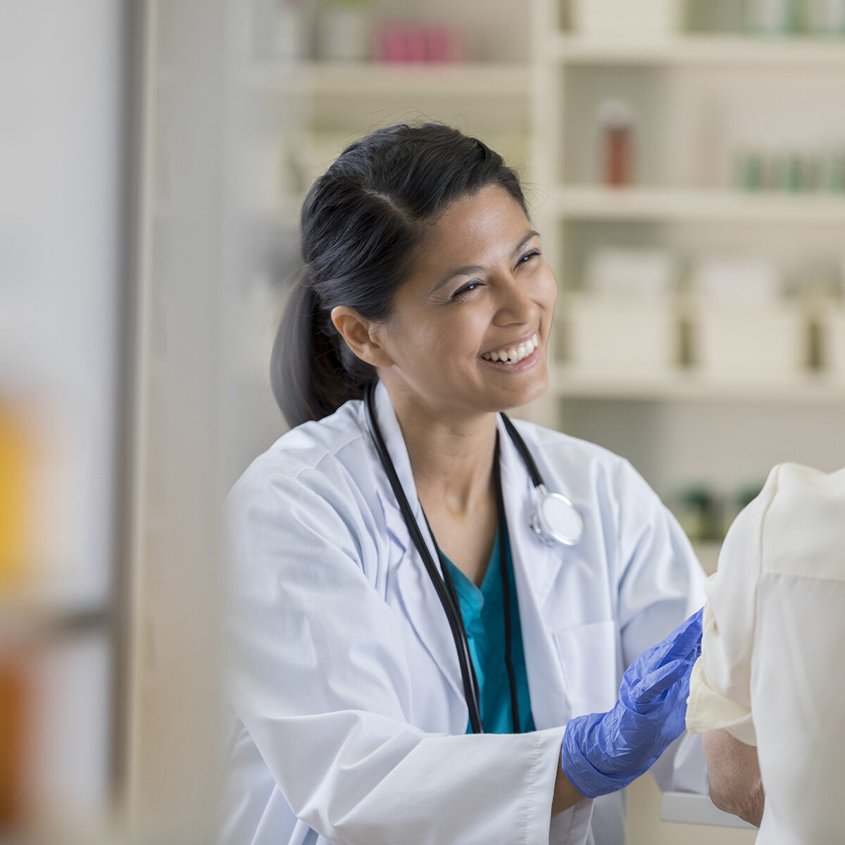 Smiling pharmacy employee gives vaccine to elderly woman with back to camera